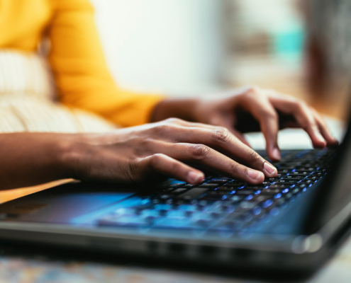 Side view of someone in a yellow shirt using a laptop